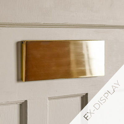 Solid brass letter box cover on a light beige door with an ex-display watermark in the corner