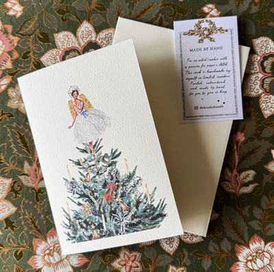 Greeting card with angel design on a floral patterned surface