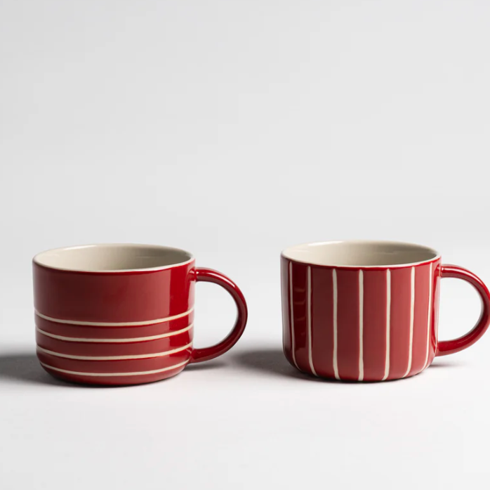 Two red mugs with white stripes on a light gray background