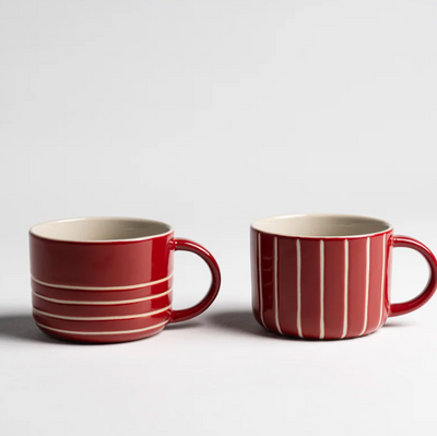 Two red mugs with white stripes on a light gray background