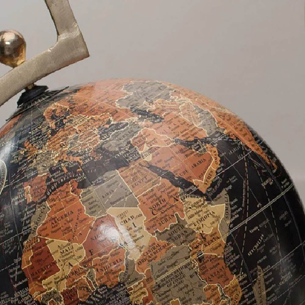 Close up of a large decorative globe featuring black, burnt orange, khaki green and yellow map imagery against a pale background
