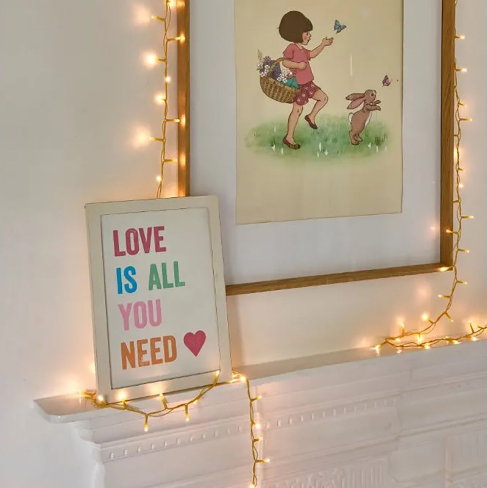 Warm white led fairy lights with a yellow cable draped around a picture frame of a child and a rabbit