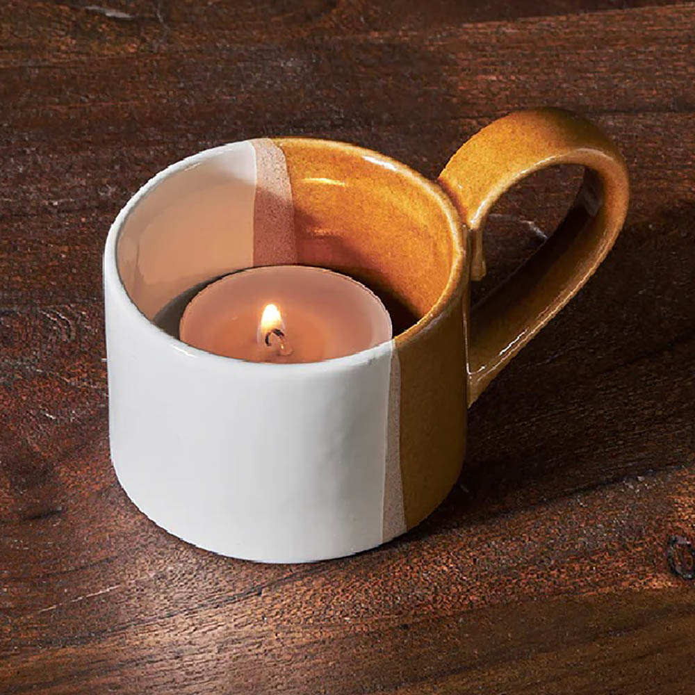 White and terracotta tealight holder in a teacup style with lit candle inside