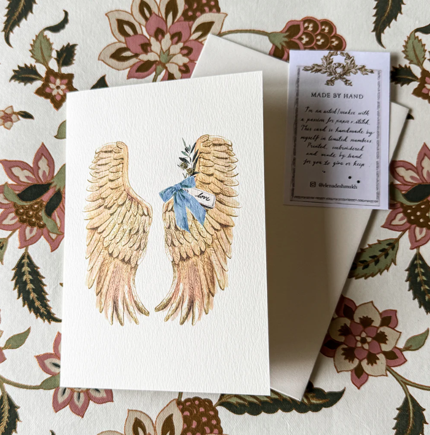 Card with angel wings illustration on a floral background