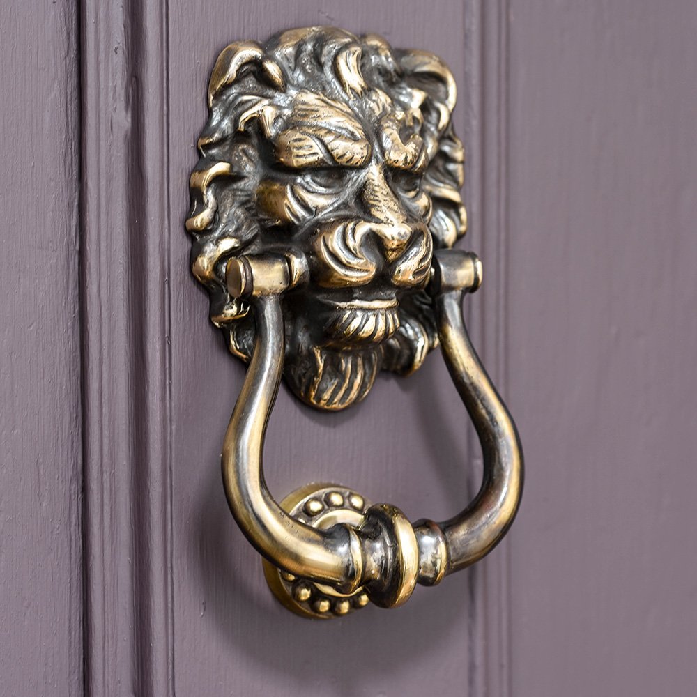 Aged brass lion's head door knocker on purple door