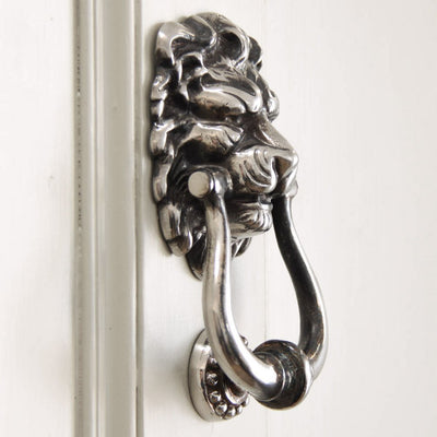 Aged nickel lion's head door knocker side view