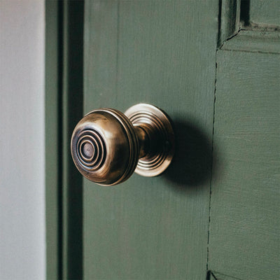 Polished antique brass regency bloxwich door knob on green wooden door