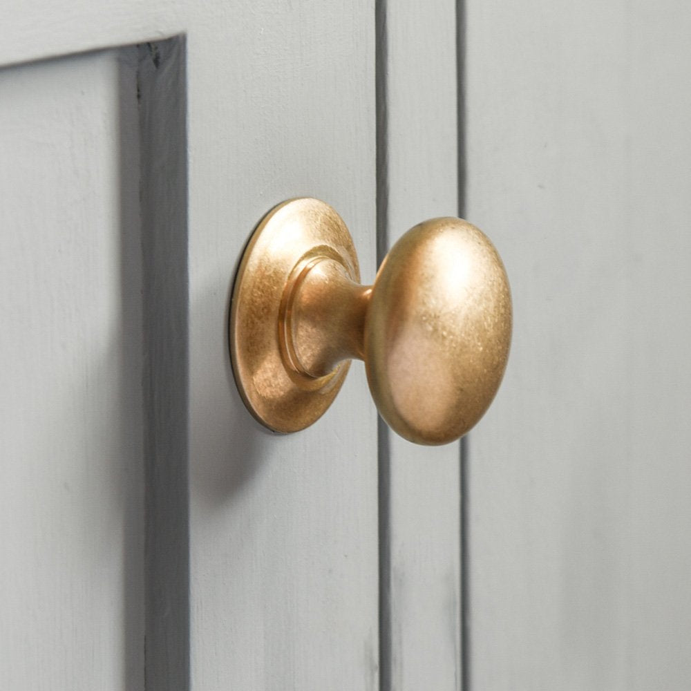 Aged Brass Round Cabinet Knob fitted to a light grey cabinet door