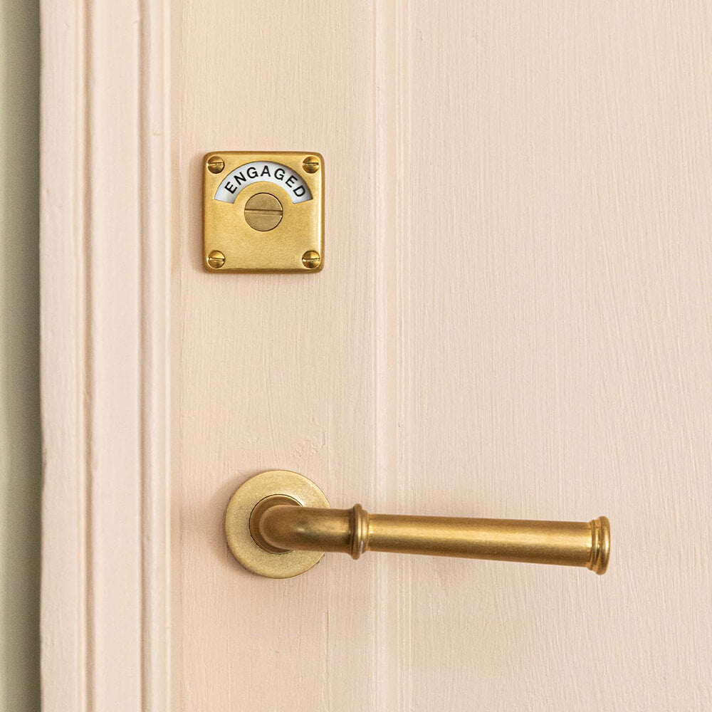 toilet door lock in aged brass on pink door with aged brass lever handles