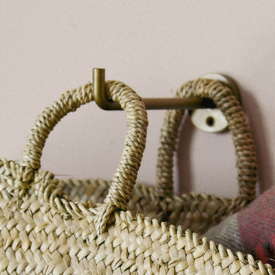 Aniko brass hook suspending shopping bag seen on angle on a pink wall