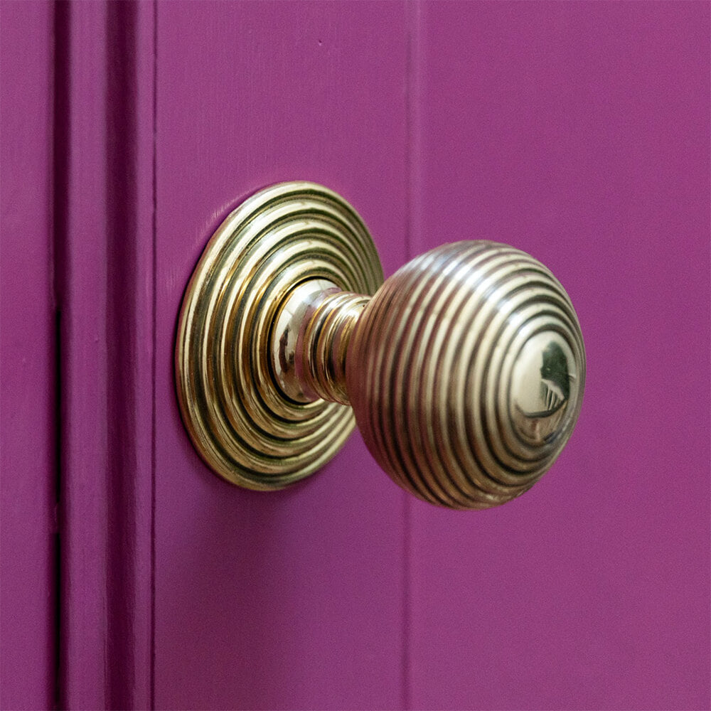 Beehivee aged brass door pull on a bright pink front door