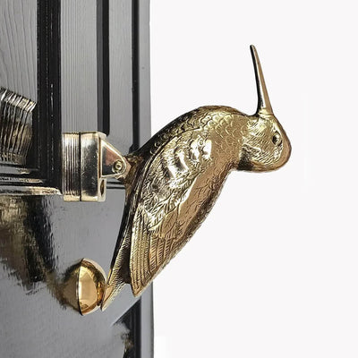 Brass bird door knocker on a black door