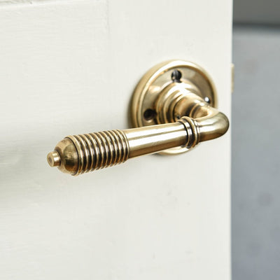 A photo showing the aged brass and detail of a reeded lever handle