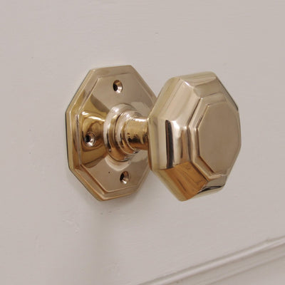 Brass octagonal door knob on pale pink door