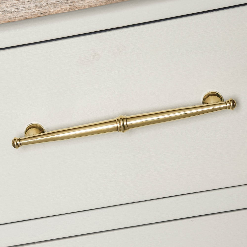 A regency pull handle with an aged brass finish on a chest of drawers
