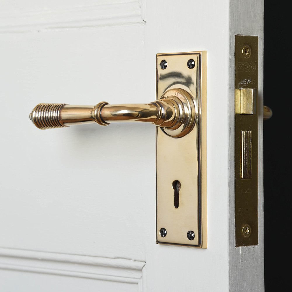 A reeded lever handle with keyhole backplate in an aged brass finish