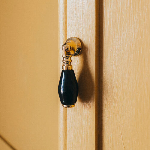 Brass and black ceramic drop pull on yellow cupboard