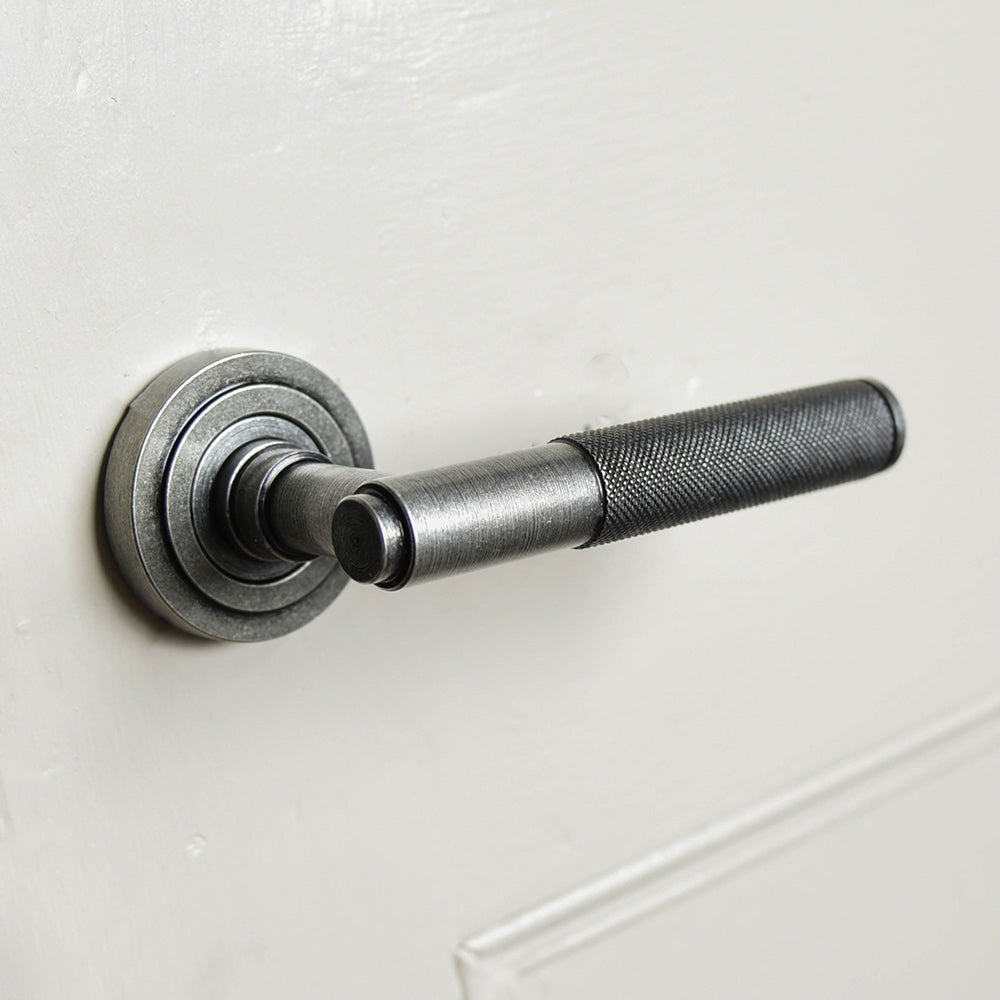 A Brompton lever handle in a pewter finish fitted to a door