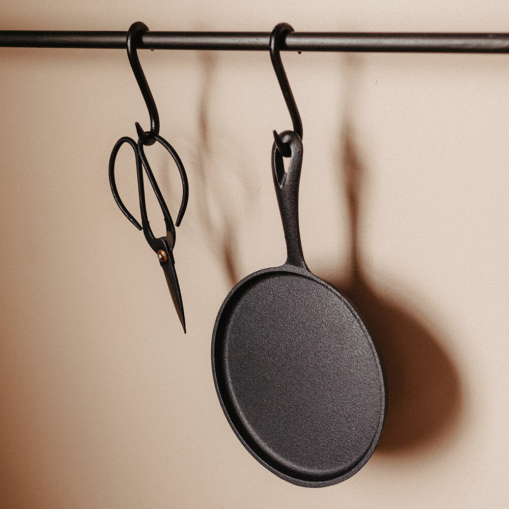 Cast iron crepe pan and scissors hanging from rail