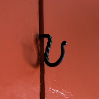 black twisted cup hook on red door