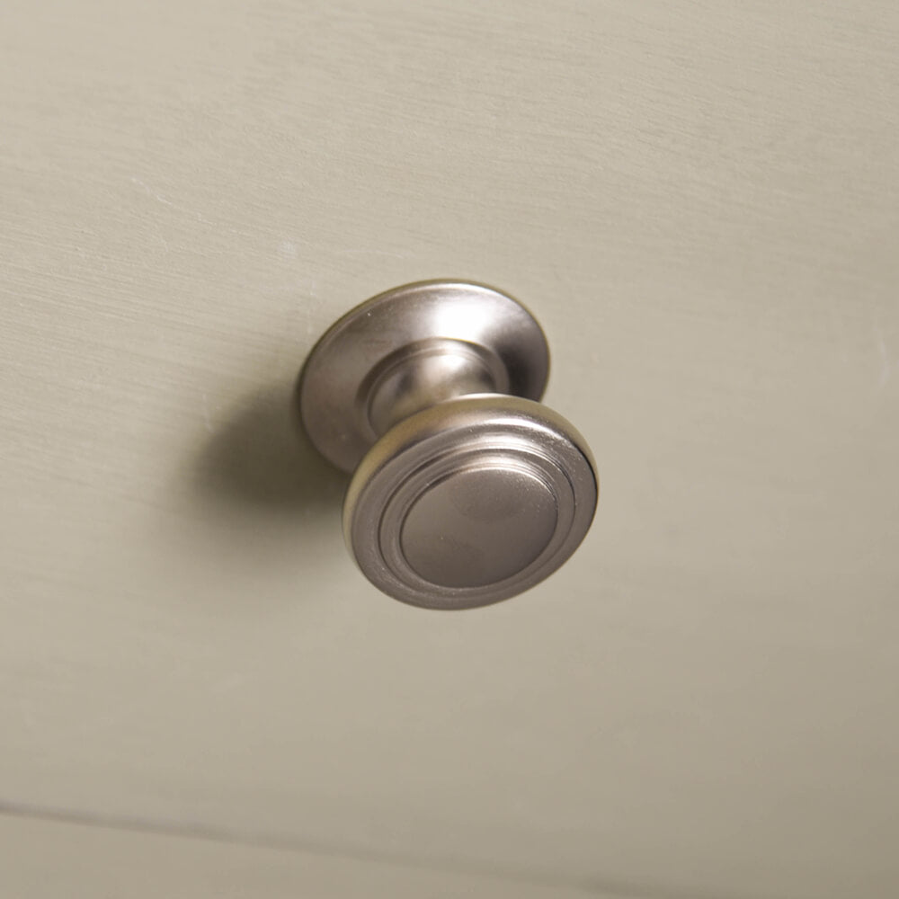 Detail of Stepped cushion cabinet knob in satin nickel on green drawers