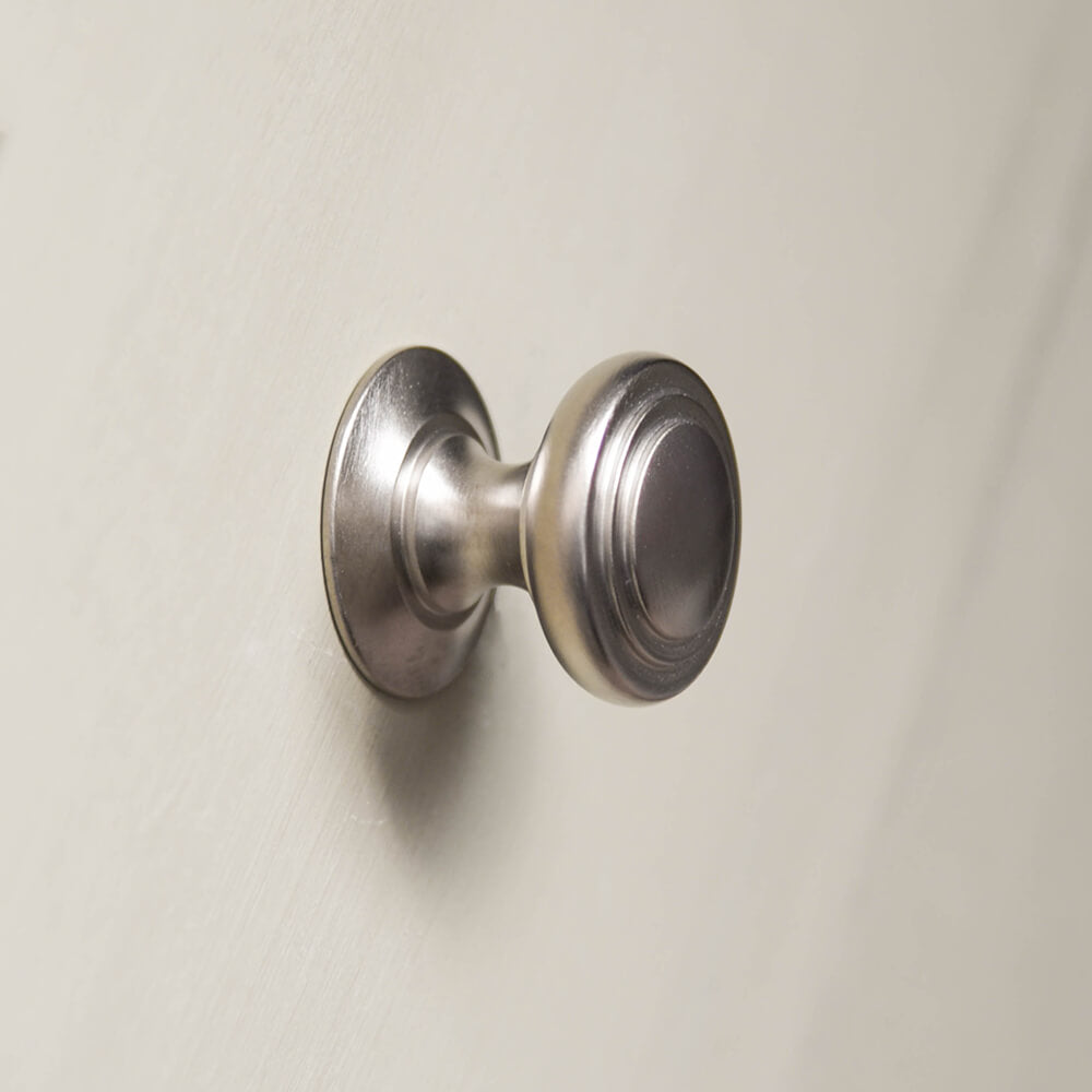 Stepped cushion cabinet knob in satin nickel on green drawers