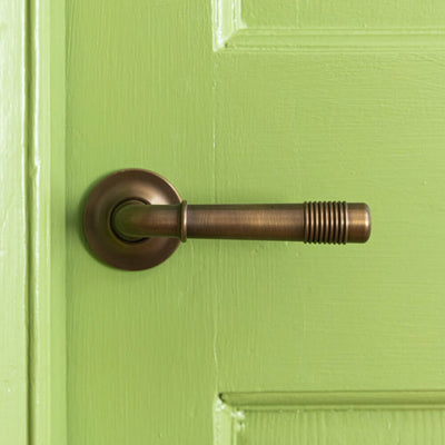 Distressed Antique Brass Crest Lever Handles on Covered Rose on green door