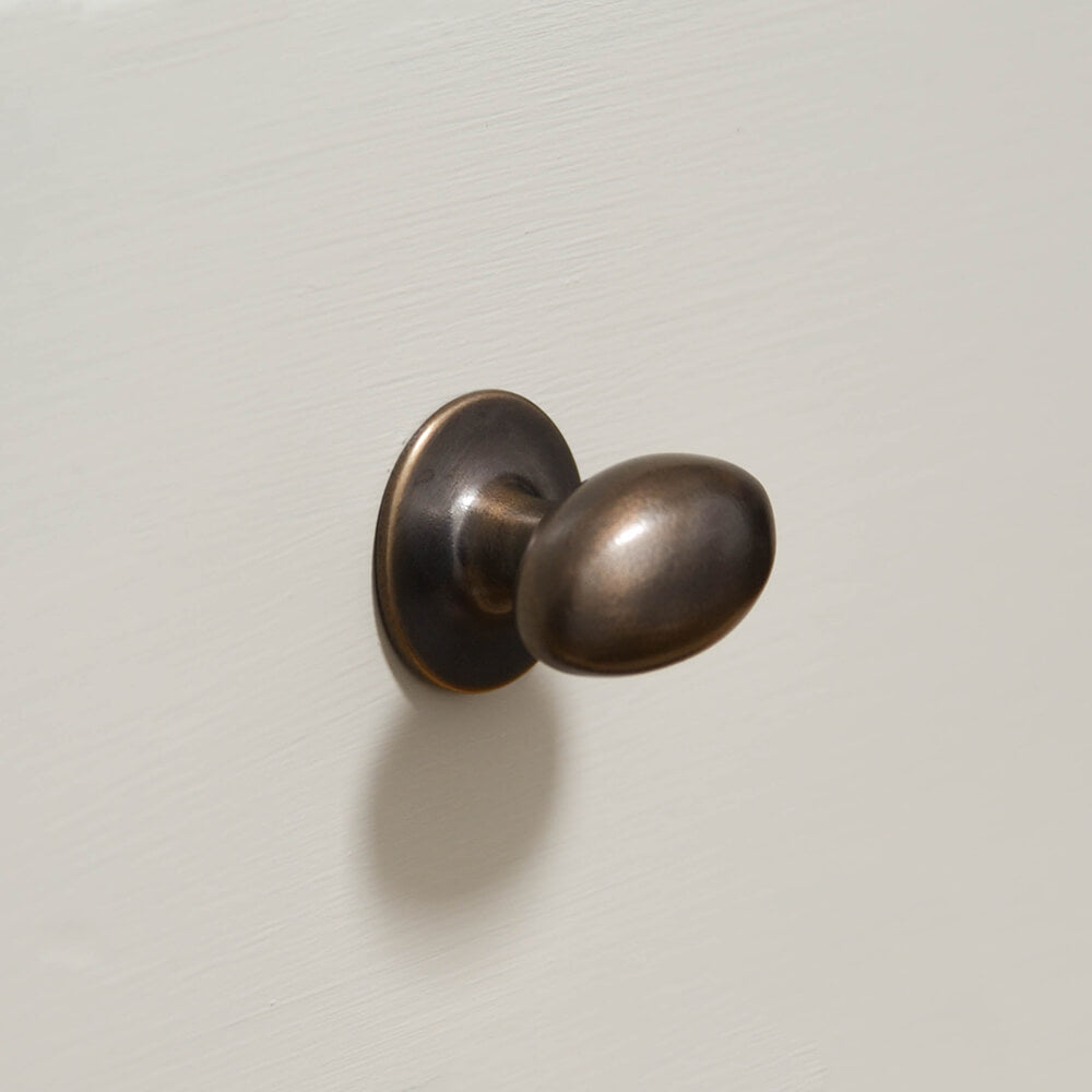 oval cabinet knob on cream drawers in distressed antique brass which is a living finish