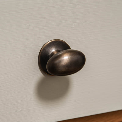 oval cabinet knob on cream drawers in distressed antique brass which is a living finish from front