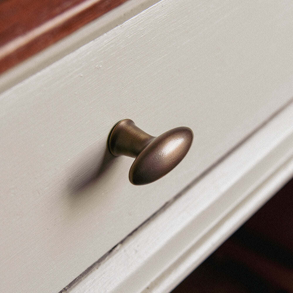 Distressed Antique Brass Zeppelin Cabinet Knob on a drawer front in a kitchen