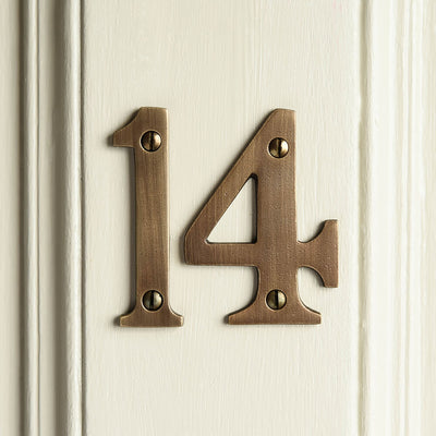 Numbers 14 in distressed antique brass seen on a front door