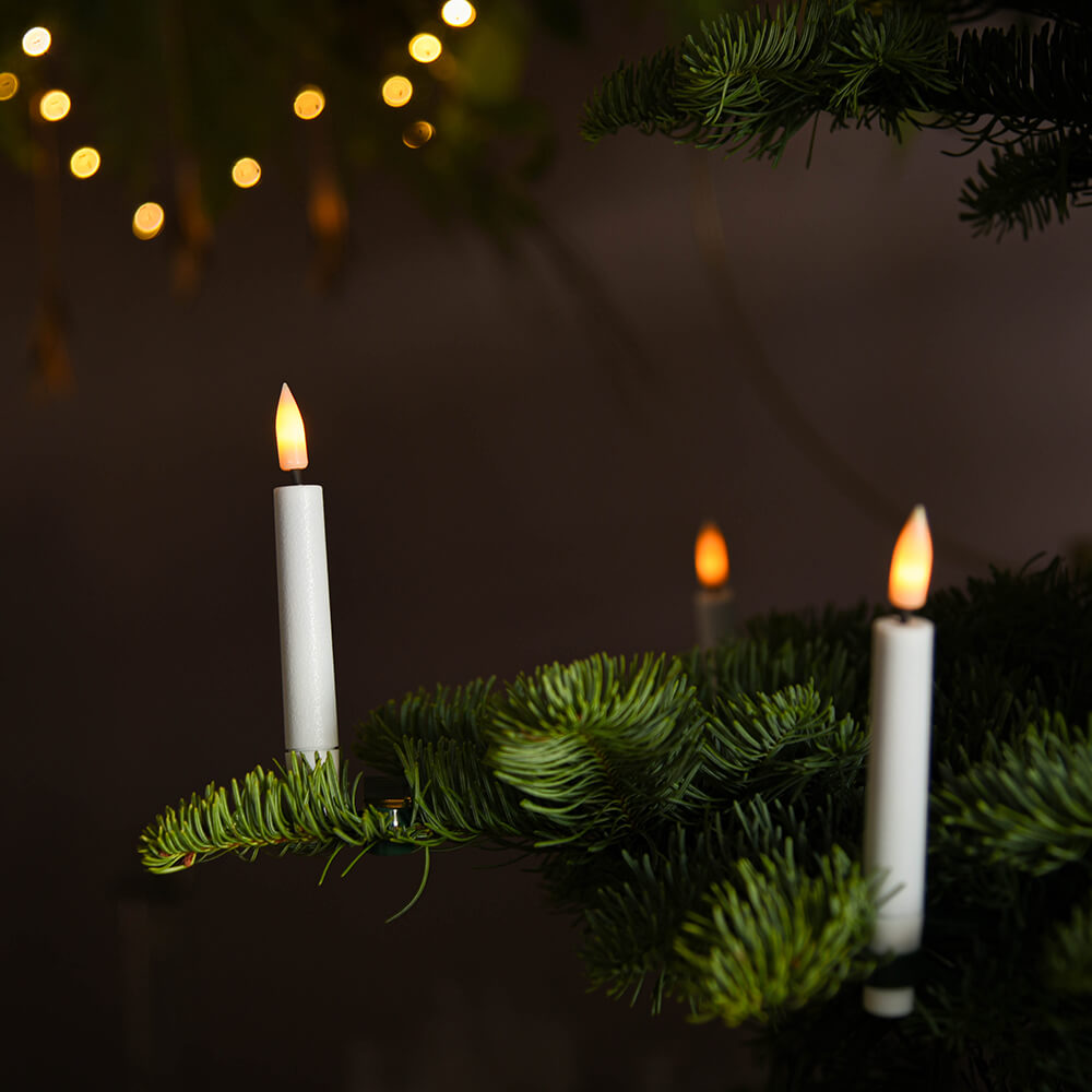LED tree candles seen on the branches of a pine tree