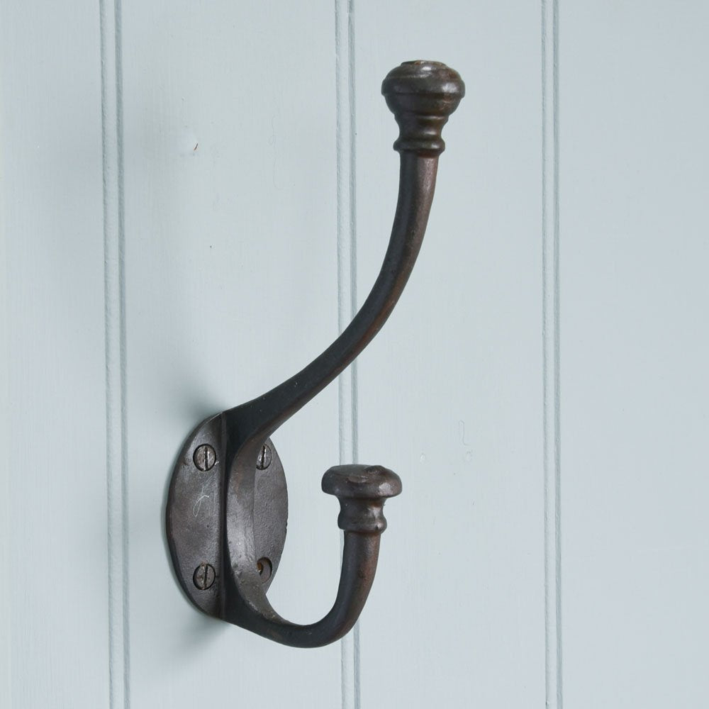 A large double coat hook in a black beeswax finish fitted to a wall