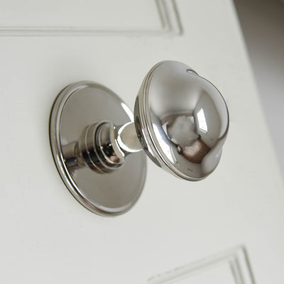 Large round polished nickel door pull on white background
