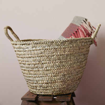 Large berber basket used for blanket storage on a stool