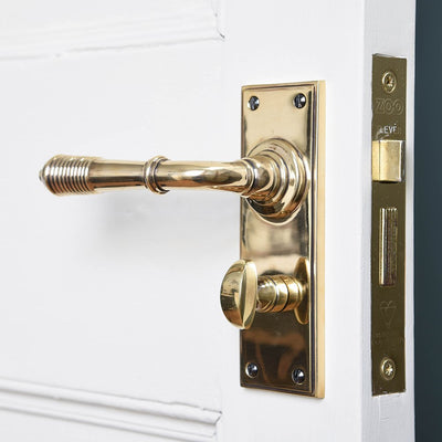 A reeded lever handle with bathroom lock fitted in postiion on a door