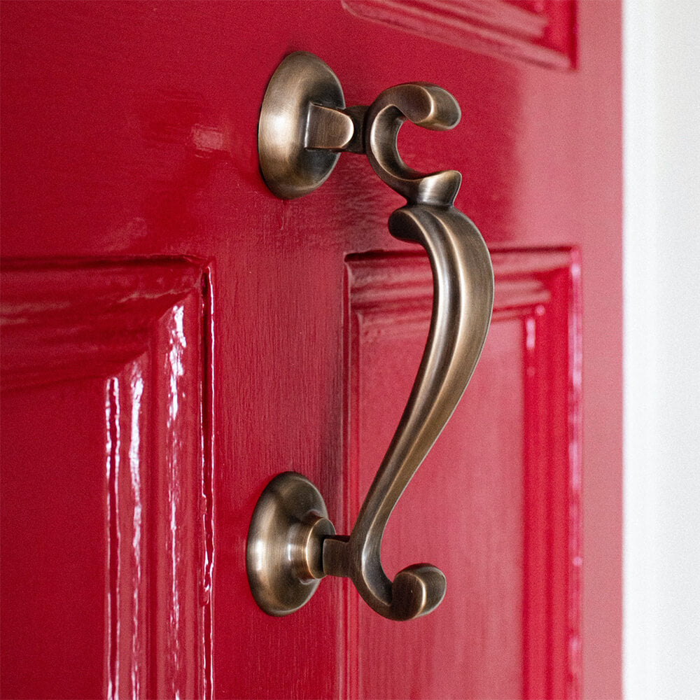 Light Antique Brass Door Knocker on red door seen from the side
