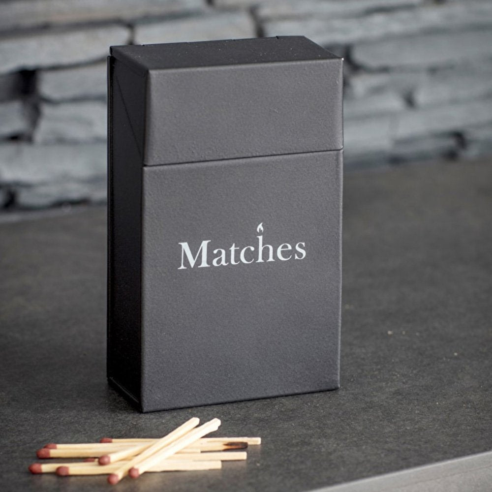 A powder coated steel storage tin to hold matches or lighters. Painted in a dark carbon grey finish with 'Matches' printed across the front in white
