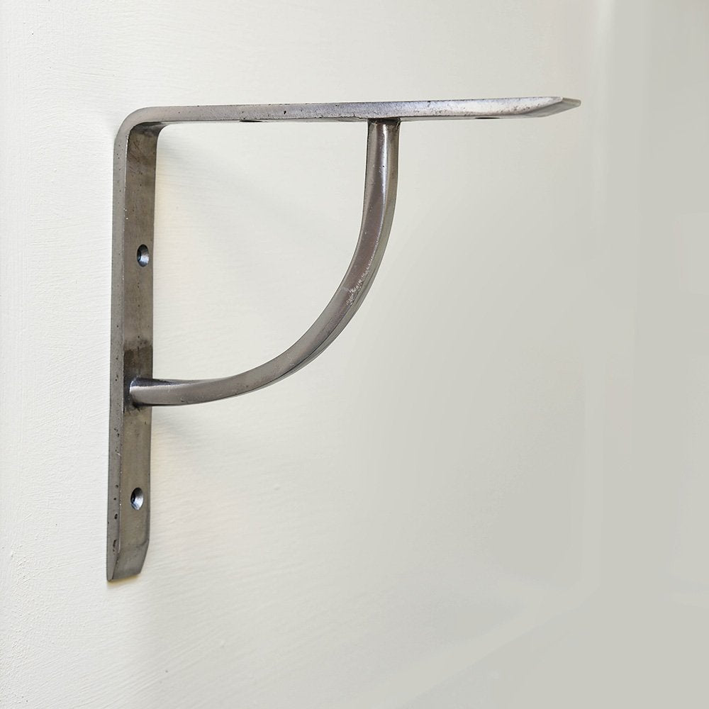 A plain shelf bracket in a natural iron finish in situ