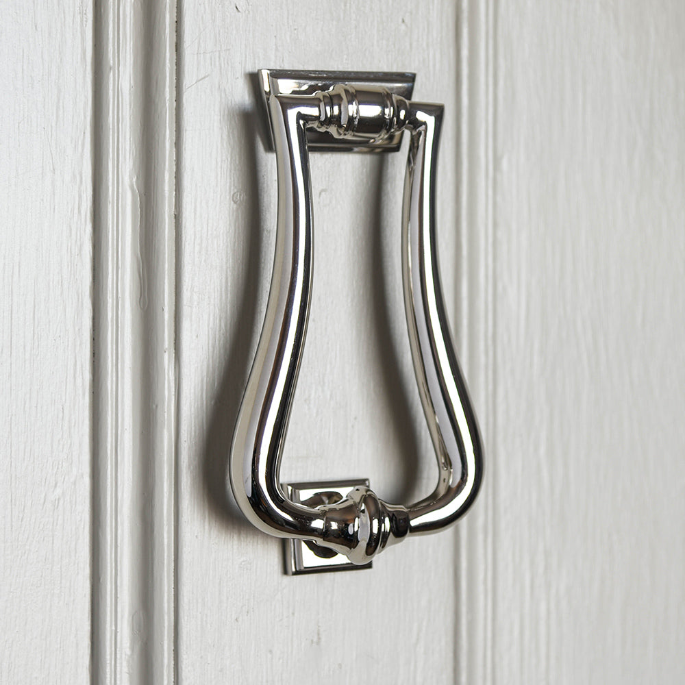 An Art Deco style door knocker in polished nickel fitted to a door
