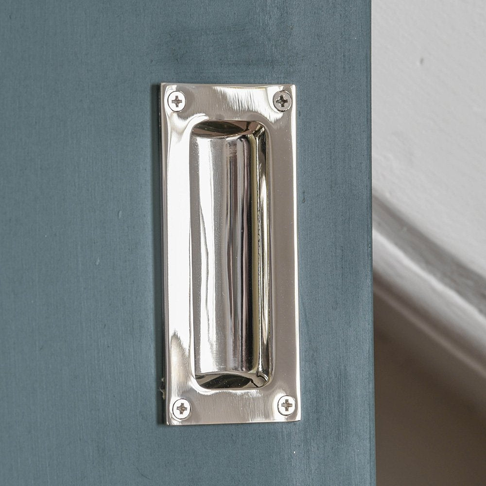 A flush door handle fitted to a cupboard showing the polished nickel finish