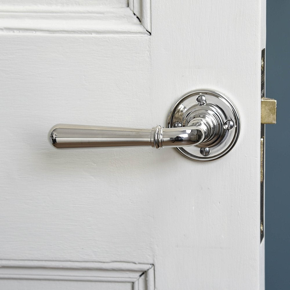 A Newbury Lever Handle with rose backplate in polished nickel finish fitted in place to a door