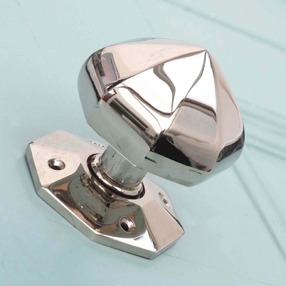 Pointed octagonal door knobs in polished nickel on a blue background