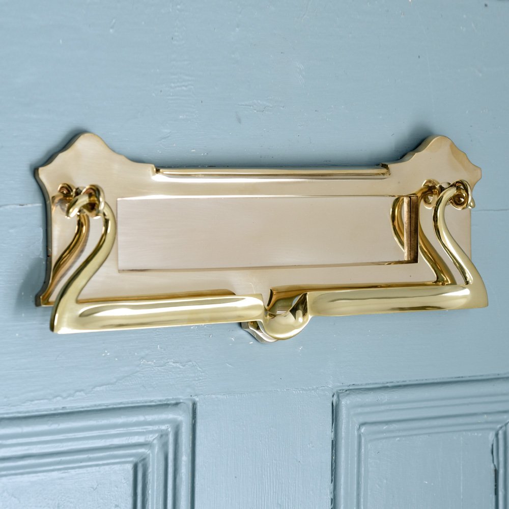 A postal Letterplate in a Brass finish with a drop pull clapper fitted to a door