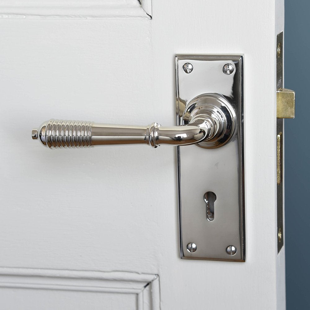 A reeded lever handle with keyhole backplate in polished nickel