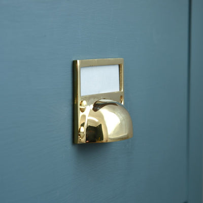 A side photo of a Hooded Drawer Pull with Card Frame in Polished Brass showing depth of drawer pull on a blue drawer
