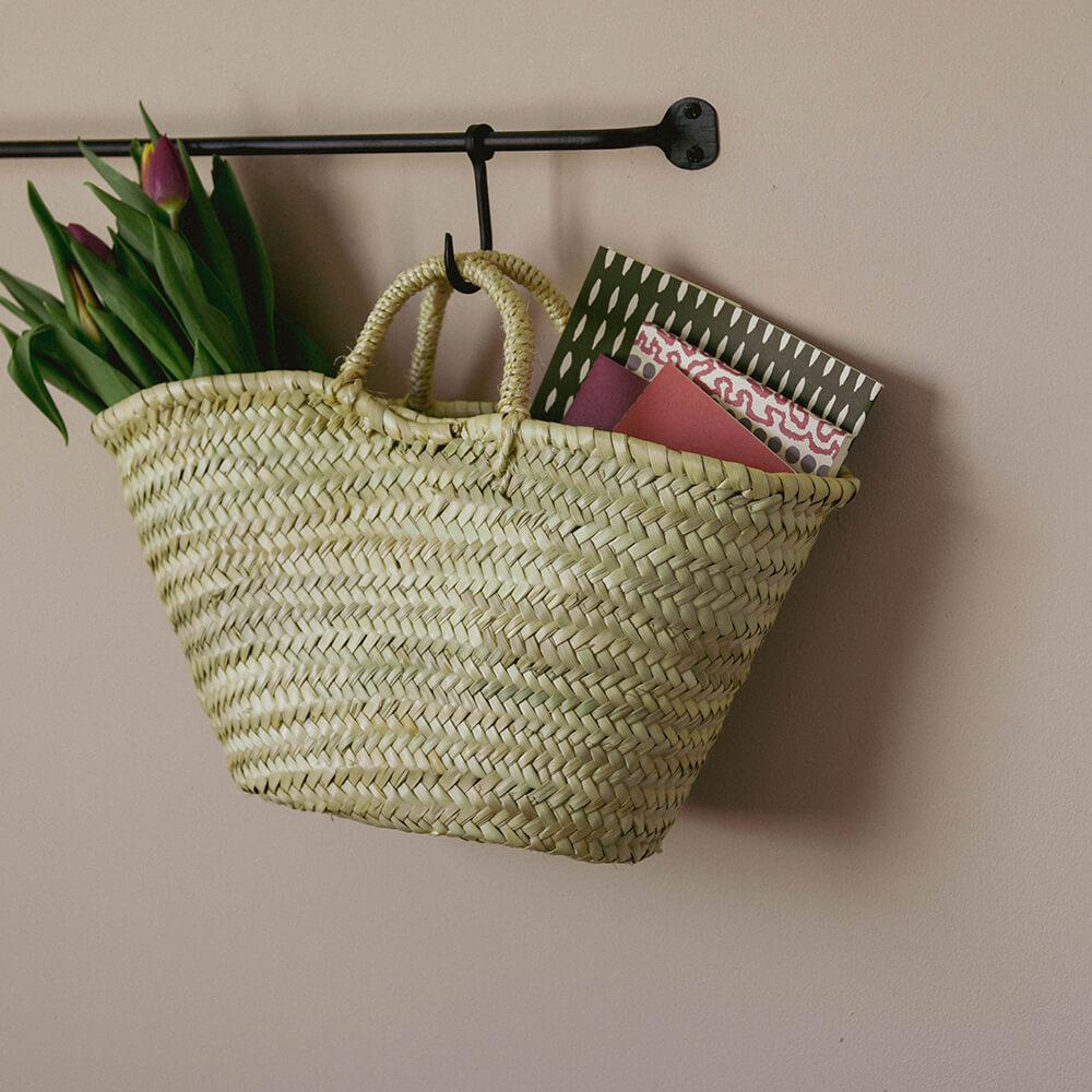 Small shopping basket hung on wall with blanket inside
