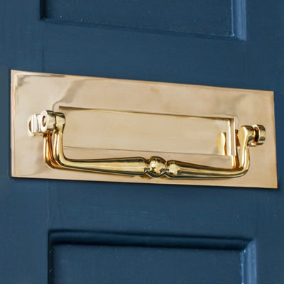 Traditional brass letterplate with clapper on blue door