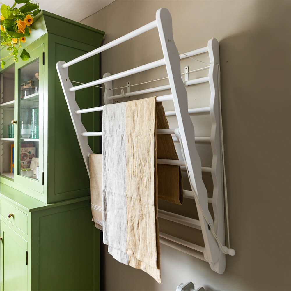 Wide White Julu clothes airer seen on the wall with green dresser shown partially opened