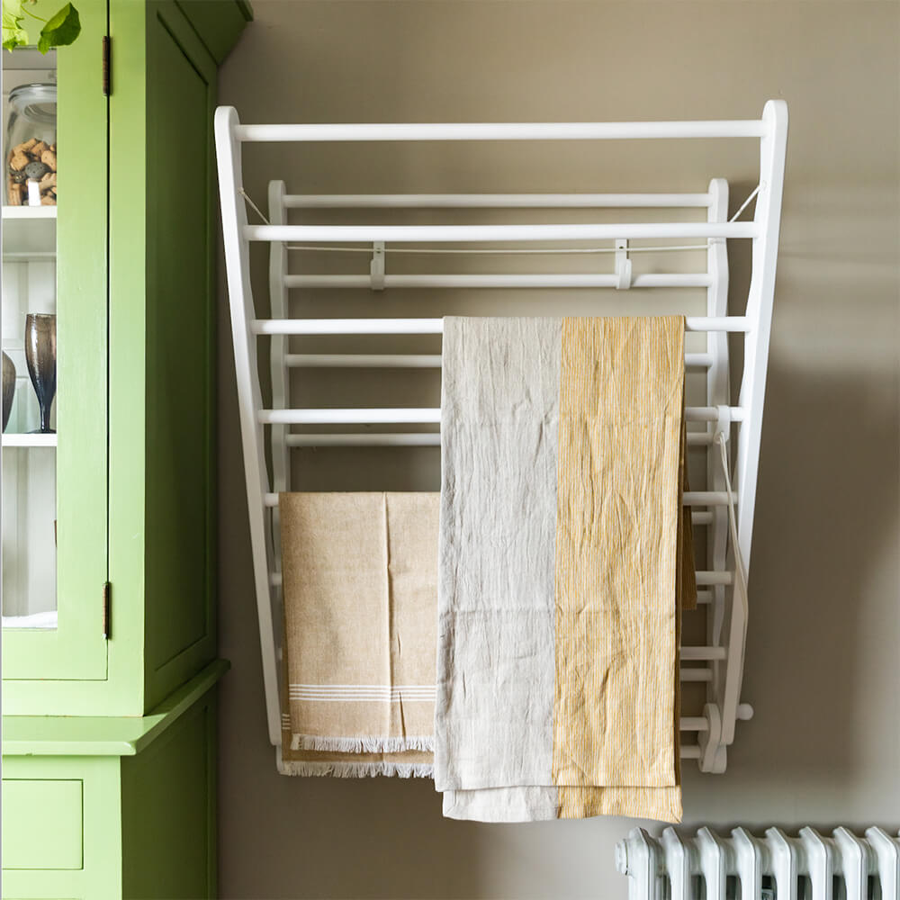 Wide White Julu clothes airer seen on the wall with green dresser shown from front
